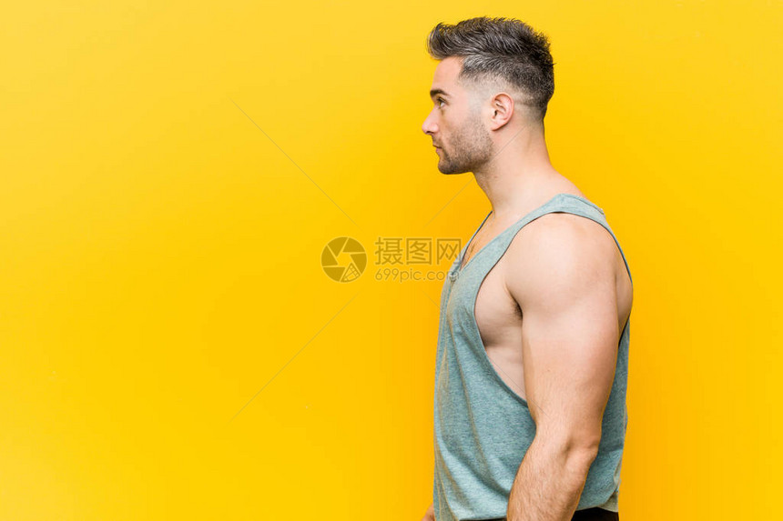 年轻健身人面对黄色背景的左图片