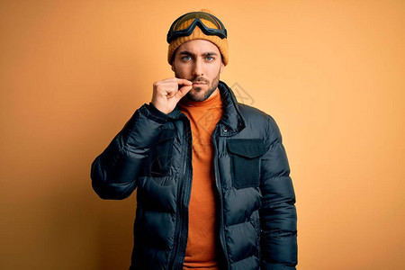 长着大胡子穿着雪运动服和滑雪护目镜的年轻帅气滑雪者图片