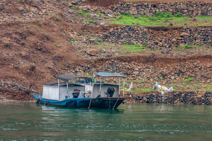 大宁河上的龙门峡谷黑色和蓝色小船特写镜头沿绿色和棕色土海岸线停泊在翠图片