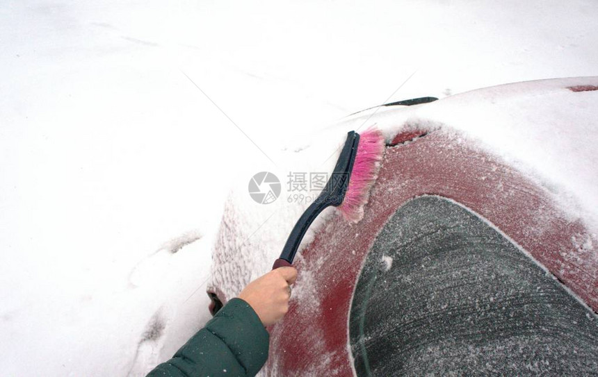 下雪后女孩从雪中清理汽车图片