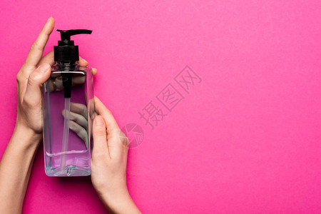 女人拿着瓶子和粉红色洗手液的剪影图片