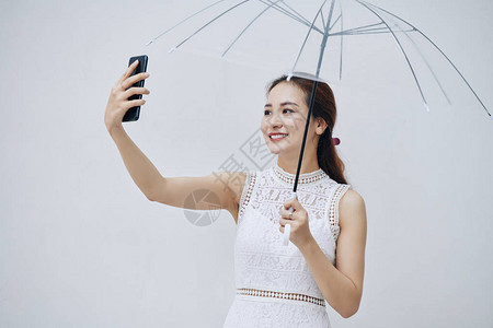 美丽的亚洲年轻女在与透明伞说话时笑图片
