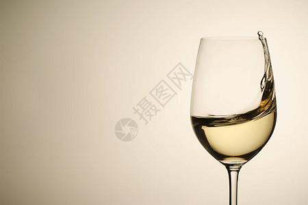 悬浮小滴子和白葡萄酒在时尚的玻璃葡萄酒杯中喷洒图片