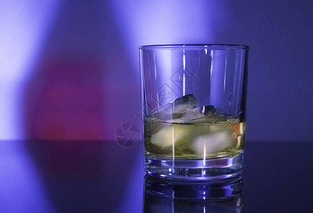 蓝粉色灯光下加冰的玻璃威士忌酒杯图片