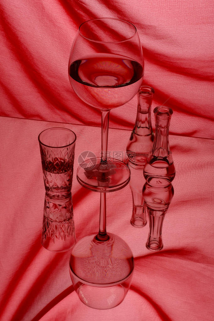 红底白葡萄酒的玻璃杯和玻璃瓶图片