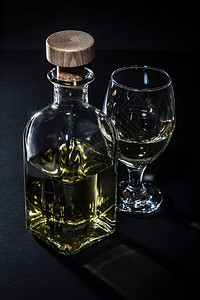 黑色背景上的瓶子和白葡萄酒杯的前视图图片