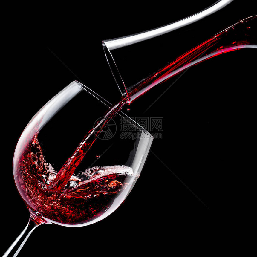 红酒被倒入黑色背景的酒杯中图片