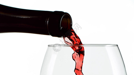 一瓶红葡萄酒倒入高叶的瓶子白图片