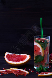 成熟的葡萄柚与黑色背景上的石榴种子的鸡尾酒排毒水饮食健康饮食和概念图片