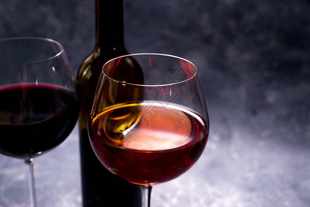 红葡萄酒瓶和杯红酒复古风格黑色背景上的红酒为您的图片