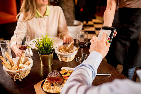 在餐厅用手机与NFC技术共进晚餐的人图片