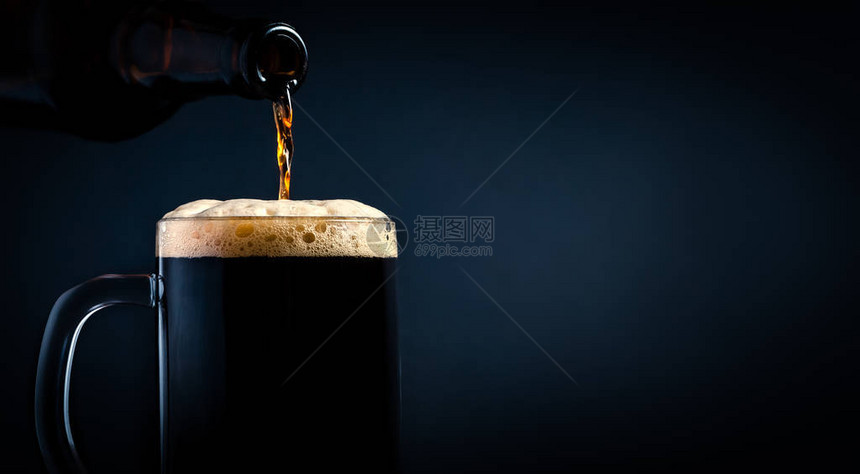 一杯黑啤酒从杯特写上在暗底图片