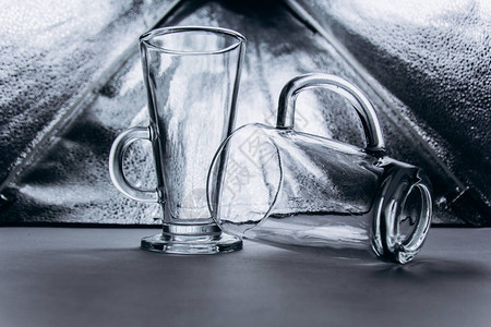 灰色银背景特写上的一副空透明玻璃眼镜两个带把手和腿的高杯子复制空间图片