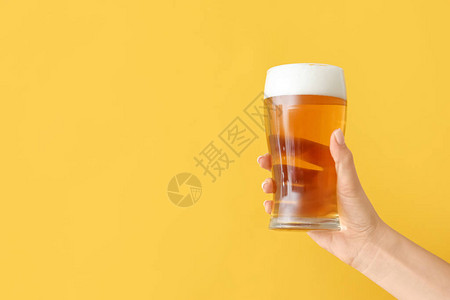 彩色背景上拿着一杯啤酒的手图片