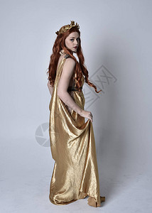 身穿长的希腊长袍和金色花圈的红头发女孩的全长肖像背景图片