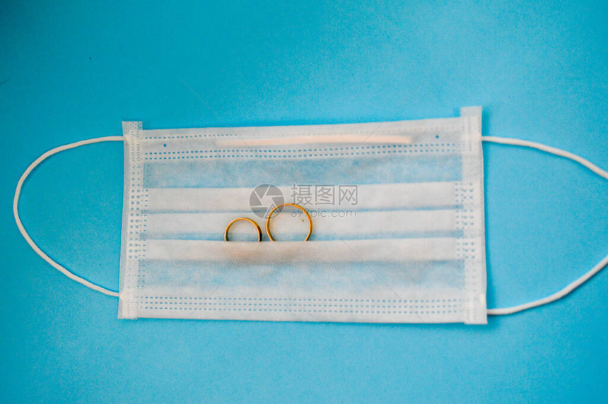 金色结婚戒指放在一次防护医用口罩上图片