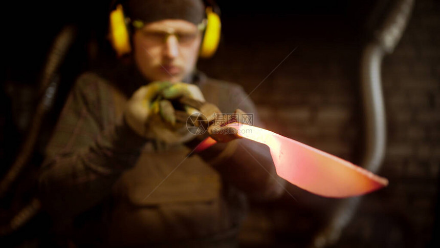 一个男人铁匠用锤子做刀子寻找不完图片