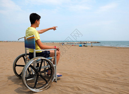在沙滩上特别轮椅上的残疾男孩表图片