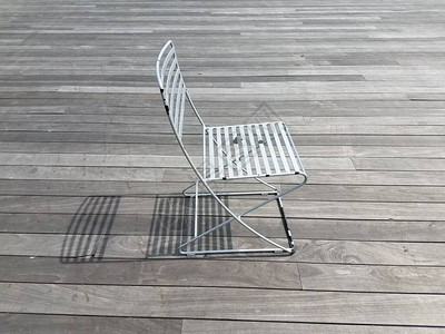 金属椅子在木板路上投下阴影图片