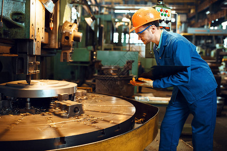 身着制服和头盔的特纳站在工厂的自动车床前工业生产金图片