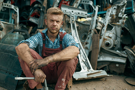 肮脏的男修理工用扳手在汽车垃圾场汽车报废汽车垃圾废弃损图片