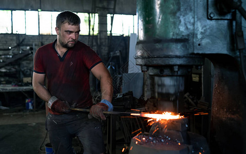 铁匠用工业锤锻造炽热的铁制品图片