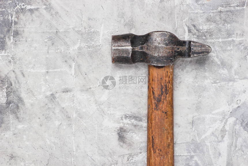 灰色混凝土背景上的旧锤子特写图片