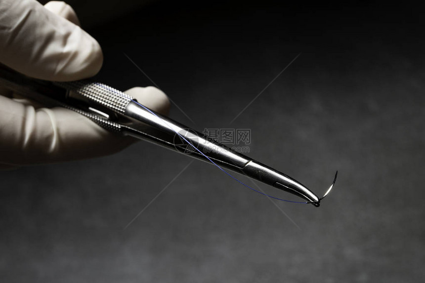 医生用蓝色尼龙手术线握住手术用针架图片