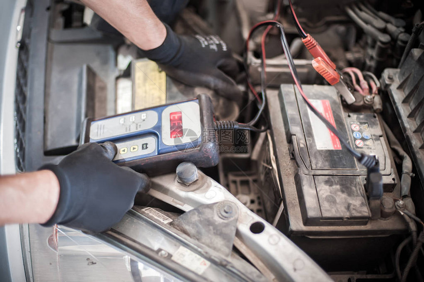汽车修理工在汽车间用数字电子池测试仪和分析仪检查和测图片