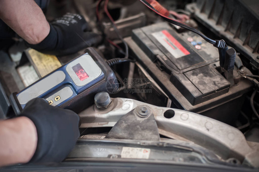 汽车修理工在汽车间用数字电子池测试仪和分析仪检查和测图片
