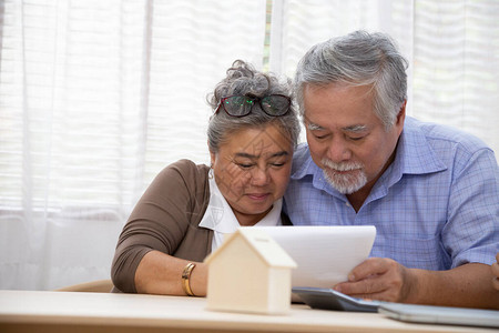 亚洲高龄夫妇签订署合同购买新房子房地产和贷款房屋融资概念的图片