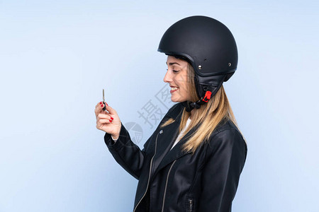 年轻金发女金发美女戴着摩托车头盔和钥匙超过孤图片