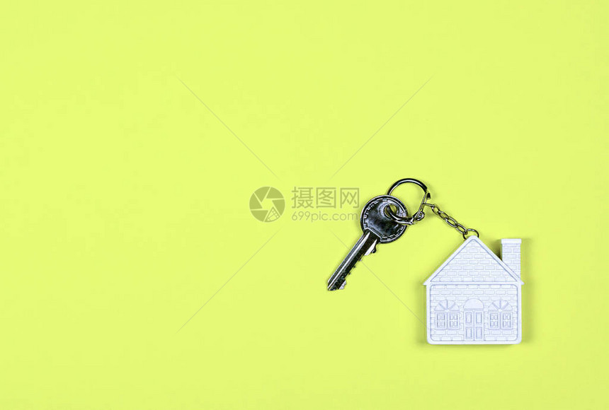 一个白色房子形式的钥匙链和黄色背景上的一把小金属钥匙购买销售租赁房地产抵押贷款邻居图片