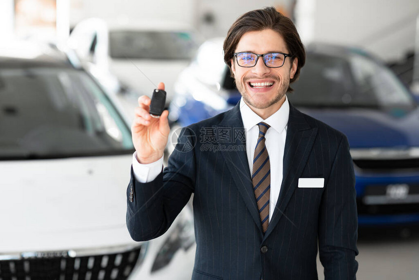 成功销售员在Inspects显示自动键的英俊特工站在汽车租赁办公图片