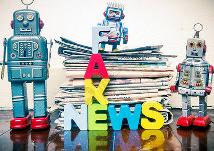 三台复古机器人一堆旧报纸在木地板上写图片