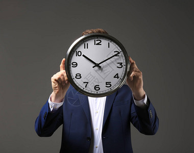 在深色背景上带时钟的商人时间管理念背景图片
