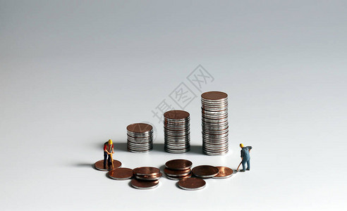 劳动和创造收入的概念一叠硬币和两个小人图片