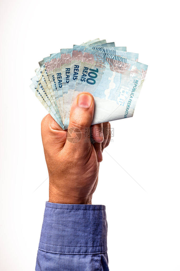 由男手持的巴西100瑞瓦钞票是孤立的白种背景图片