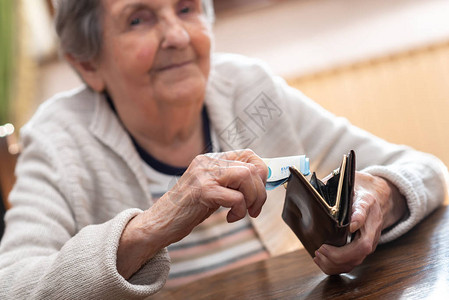 老妇人从钱包里拿出一张钞票图片