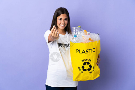 年轻巴西女人拿着一袋装满塑料瓶的塑料瓶图片