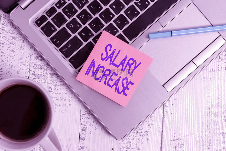 写笔记显示加薪增加员工资或薪酬的商业理念时尚金属笔记本电脑粘垫笔咖啡杯躺图片