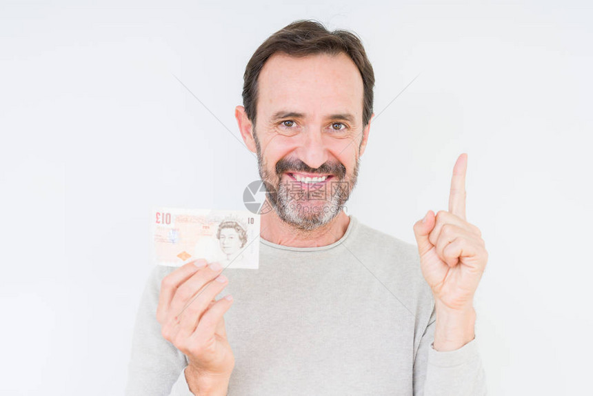 老人在孤立的背景下拿着十英镑的钞票图片