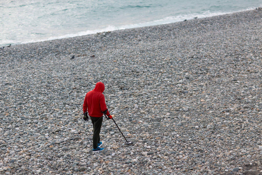 有金属探测器的人在沙滩上寻图片