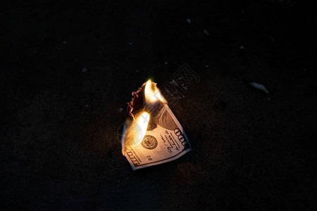 在混凝土地板上燃烧的美元钞票特写图片