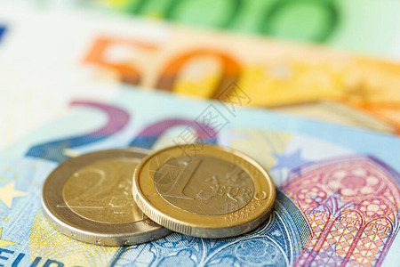 在钞票背景的一枚和两枚欧元硬币图片