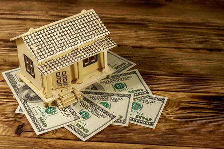 房子模型和我们在木制背景上的一百美元钞票物业投资房屋贷款房屋抵押图片