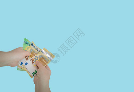 位白人妇女手持一捆新的200和100欧元钞票的特写图片