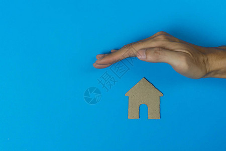 财产保险概念一只男人的手保护着一座由蓝色背景上剪纸图片