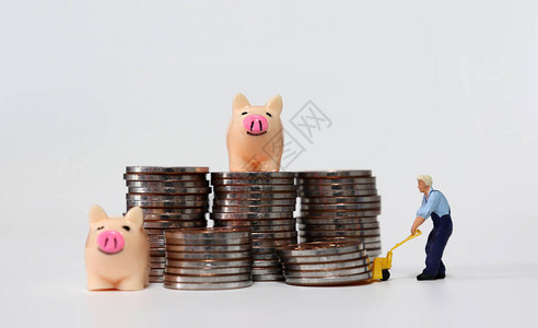一个迷你人携带着一堆硬币两只微型小猪银行图片
