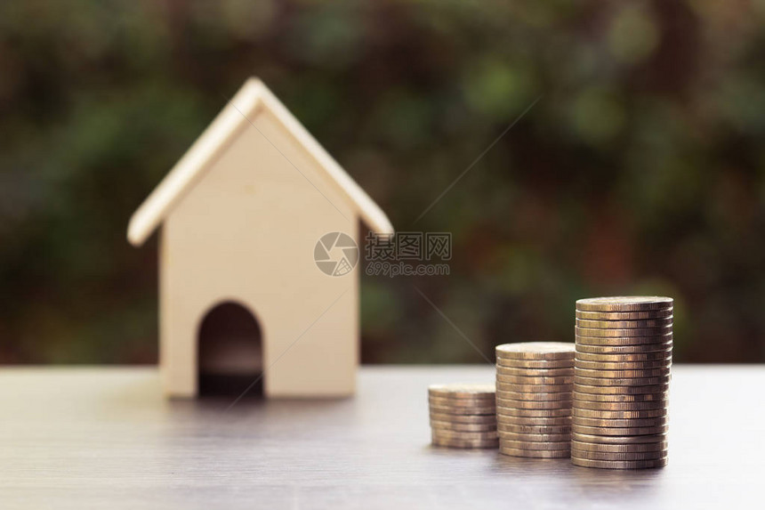 房地产投资和家庭金融抵押贷款概念堆叠的硬币和模糊的房子模型木桌与自然背景描述房屋投资或持续图片